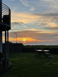 a picnic table in a yard with the sunset in the background at Beachside Ground Floor Flat in Birchington