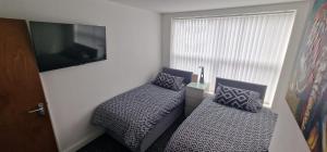 a bedroom with two beds and a tv on the wall at LFC Anfield Guest House in Liverpool