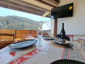 a dining room table with wine glasses and a television at Studio Pra-Loup, 1 pièce, 6 personnes - FR-1-165A-74 in Uvernet