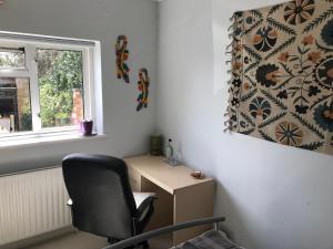 einen Stuhl in einem Zimmer mit einem Schreibtisch und einem Fenster in der Unterkunft Cozy double bedroom in stunning Bungalow on River Thames - near Thorpe Park/Royal Holloway University/20mins from Heathrow in Staines upon Thames + 34 Fotos