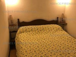 ein Schlafzimmer mit einem Bett mit einer gelben Blumendecke in der Unterkunft Appartement Les Angles, 2 pièces, 6 personnes - FR-1-295-141 in Les Angles