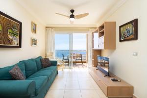 ein Wohnzimmer mit einem blauen Sofa und Meerblick in der Unterkunft Home2Book Amazing Sea Views & Terrace, El Porís in Poris de Abona