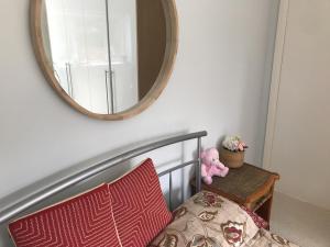 ein Teddybär, der auf einem Bett unter einem Spiegel sitzt in der Unterkunft Cozy double bedroom in stunning Bungalow on River Thames - near Thorpe Park/Royal Holloway University/20mins from Heathrow in Staines upon Thames