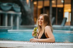 a woman in a swimming pool holding a drink at Tallink Spa & Conference Hotel in Tallinn
