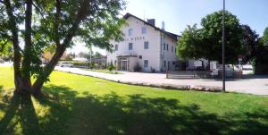 ein großes weißes Gebäude mit einem Baum im Gras in der Unterkunft Hotel Schlee in Hohenschäftlarn