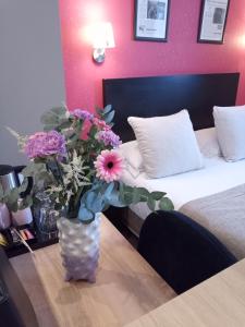 eine Vase mit Blumen auf einem Tisch in einem Hotelzimmer in der Unterkunft Be Cottage Hotel in Le Touquet-Paris-Plage