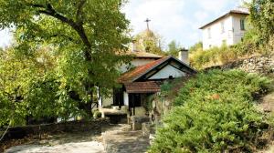 a small white house with a cross on a hill at Hadjigabarevata Kashta in Dŭlbok Dol