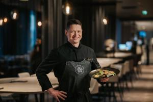 a man in an apron holding a plate of food at Tallink City Hotel in Tallinn
