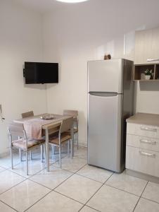 Il comprend une cuisine équipée d'une table et d'un réfrigérateur blanc. dans l'établissement Sunset home Baia Blu, à Gallipoli