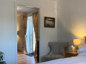 1 dormitorio con cama, silla y espejo en Clashmore Wood en Dornoch