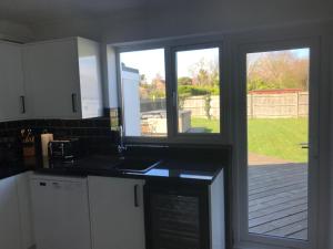 a kitchen with a view of a yard through a window at Bancroft - Camber Sands - East Sussex in Camber