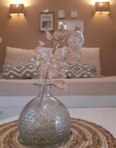 Le chalet Graines d'Amour في Grand-Champ: مزهرية مع الزهور على طاولة في غرفة النوم