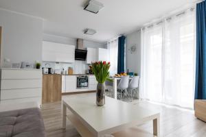 a white living room with a vase of flowers on a table at Apartament 6M Rewal w cenie basen, jacuzzi, siłownia, sala zabaw, free private parking, Park Rozrywki HOSSOLAND 30 minut in Rewal