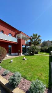 een groot rood gebouw met een tuin van groen gras bij Ivni Apartmani in Novigrad Istria