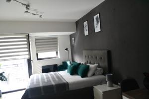 a bedroom with a bed with green pillows and a window at Urban Apartment in Niš
