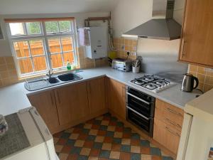 een keuken met een spoelbak en een fornuis bovenste oven bij Beaumont's Cottage in Cambridge