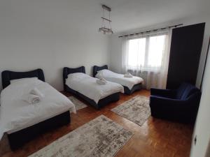 a bedroom with two beds and a chair and a window at REA Home Visoko in Visoko