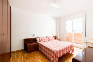 1 dormitorio con 1 cama con manta roja y blanca a cuadros en Apartamento en Parque Central en Tarragona