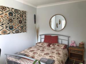 ein Schlafzimmer mit einem Bett mit roten Kissen und einem Spiegel in der Unterkunft Cozy double bedroom in stunning Bungalow on River Thames - near Thorpe Park/Royal Holloway University/20mins from Heathrow in Staines upon Thames