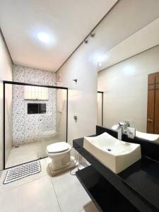 a bathroom with a white toilet and a sink at Casa Alfenas Represa Furnas c/ Piscina Aquecida 12 pessoas in Alfenas