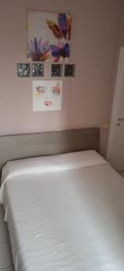 a white bed in a bedroom with paintings on the wall at Little Moon in Fontana Liri