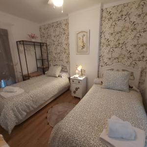 Habitación con 2 camas individuales y papel pintado con motivos florales. en Casa Rural Los Jilgueros, en Pujerra
