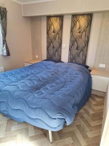 a bed with a blue comforter in a bedroom at Beach Resort Nieuwvliet Bad - NV 37 in Nieuwvliet