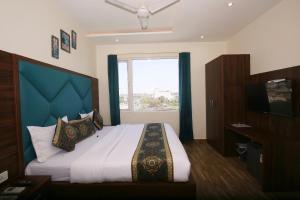 a bedroom with a large bed with a large window at Hotel East Wood Amritsar in Amritsar
