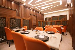 ein Esszimmer mit Tischen und orangefarbenen Stühlen in der Unterkunft Hotel East Wood Amritsar in Amritsar