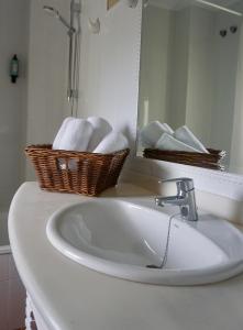 a bathroom sink with a basket of towels and a mirror at Hotel Gerra Mayor in San Vicente de la Barquera
