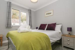 een slaapkamer met een bed met een gele deken en een raam bij Compass Point in Falmouth +29 foto's
