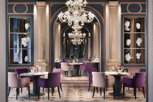 a restaurant with tables and chairs and a chandelier at Villa Cortine Palace Relais Chateaux in Sirmione