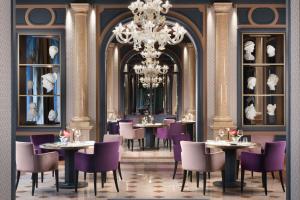 シルミオーネにあるヴィラ コルティーネ パレス ホテルのテーブルと椅子、シャンデリアのあるレストラン