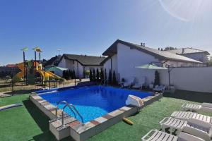 a swimming pool in a yard with chairs and a playground at Cottage, 2 bedrooms, swimming pool, Grzybowo in Grzybowo