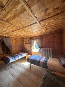 a bedroom with two beds in a wooden cabin at Rifugio Teggiate in Madesimo