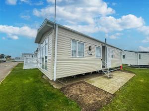a white house with a porch on a lawn at Modern 6 Berth Caravan With Free Wifi Nearby Pakefield Beach Ref 68028cr in Lowestoft
