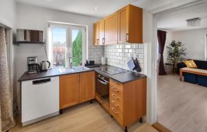 a kitchen with wooden cabinets and a white dishwasher at Lovely Home In Lvestad With House A Panoramic View in Lövestad