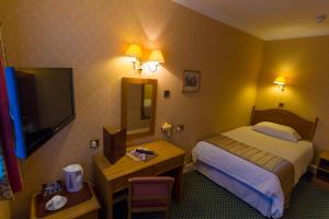 ボーンマスにあるThe Trouville Bournemouthのベッド、デスク、テレビが備わるホテルルームです。