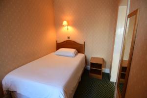 a small bedroom with a white bed and a mirror at The Trouville Bournemouth in Bournemouth