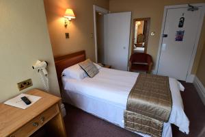 um quarto de hotel com uma cama e uma secretária em The Trouville Bournemouth em Bournemouth