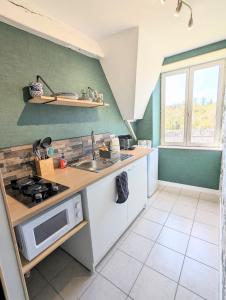 eine Küche mit einer Spüle und einer Mikrowelle in der Unterkunft Studio Silhem in Saint-Germain-les-Belles