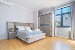 a white bedroom with a bed and a large window at Old Town T1 Apartment in Funchal