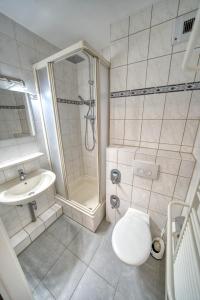 ein Bad mit einer Dusche, einem WC und einem Waschbecken in der Unterkunft Ferienpark - Haus L, App 0LEG11 in Heiligenhafen