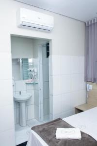 a white bathroom with a sink and a mirror at Hotel New House in São Paulo