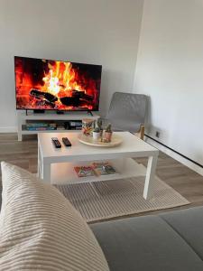 uma sala de estar com uma mesa de café branca e uma televisão em Le Lumineux em Le Mée-sur-Seine