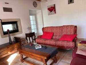 a living room with a red couch and a table at Gîte Rosalie, piscine couverte chauffée - Au bord de l'eau Conciergerie in Plouagat