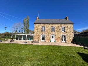 a large brick building with a grass field in front at Gîte Rosalie, piscine couverte chauffée - Au bord de l'eau Conciergerie in Plouagat