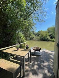 a deck with two benches and a table and a pond at The Retreat in Ditchling
