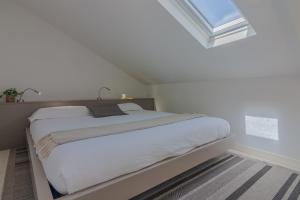 a white bedroom with a large bed with a window at Pretty Home Varenna in Varenna