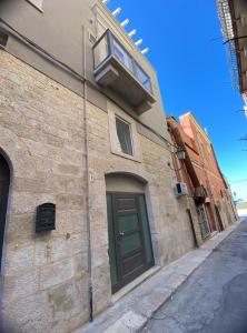 a brick building with a green door and a window at La Maison de Rosaline Rooms in Barletta